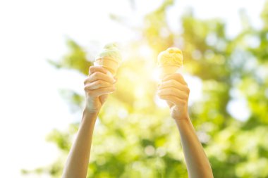 woman holding melting ice cream waffles cone in hands on summer light clipart