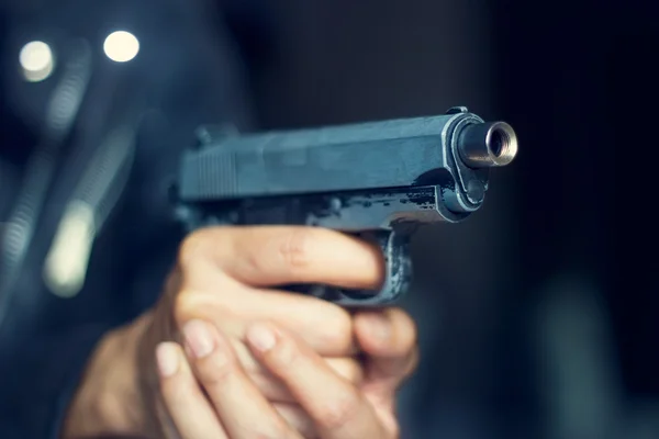 Woman pointing a gun at the target on dark background — Stock Photo, Image