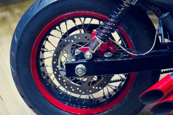 Roda traseira da motocicleta vermelha no fundo de madeira — Fotografia de Stock