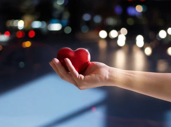 Red heart shape in woman hand on street at night, Valentine's day — Stock Photo, Image