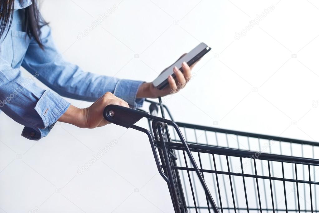 Closeup of woman with shopping cart and shopping list on smartphone