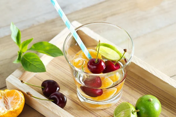 Healthy detox water, glass of cherry, orange and lime on wooden  tray — Stock Photo, Image