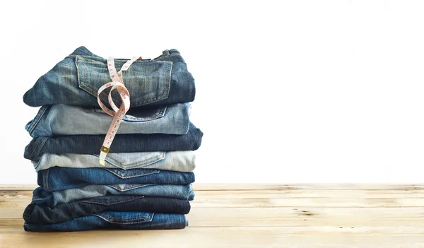 Jeans met maatregel in winkel op houten plank en witte achtergrond — Stockfoto