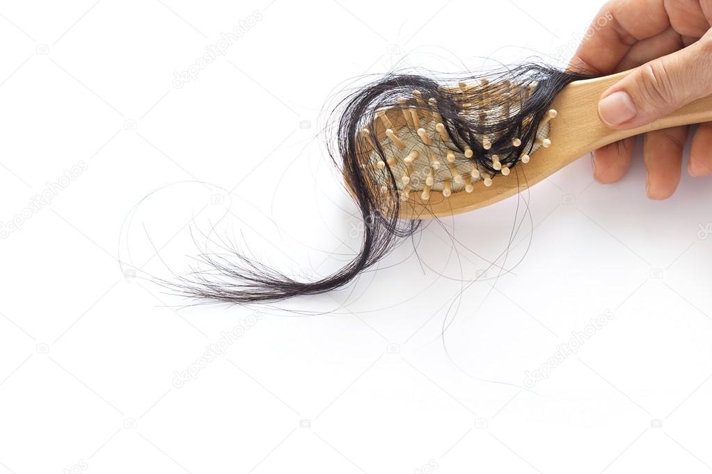 woman losing hair on hairbrush in hand