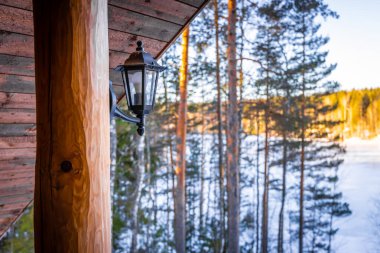 Kışın ormandaki ahşap evin feneri.