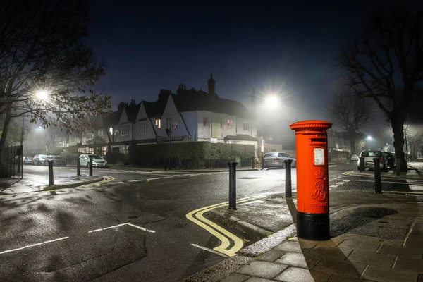 ロンドンの霧深い夜の住宅街にある古典的な赤い電話ボックス — ストック写真