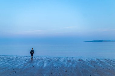 Çocuk gün batımından sonra deniz kenarında, Galler