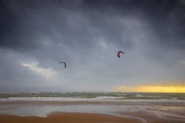 Bir uçurtma sörfçüsü, İngiltere 'nin deniz kıyısında, büyük bir kontrol edilebilir güç uçurtmasıyla rüzgarın gücünü kontrol ediyor.