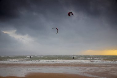 Bir uçurtma sörfçüsü, İngiltere 'nin deniz kıyısında, büyük bir kontrol edilebilir güç uçurtmasıyla rüzgarın gücünü kontrol ediyor.