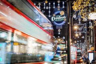 Londra 'nın kırmızı otobüsü Noel süslemeleri ve yoğun yaya trafiğiyle aydınlık bir caddeden geçiyor. Seyahat, tatil veya kentsel yaşam tarzı temaları için ideal