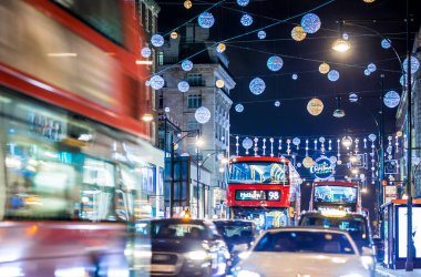 Londra 'nın kırmızı otobüsü Noel süslemeleri ve yoğun yaya trafiğiyle aydınlık bir caddeden geçiyor. Seyahat, tatil veya kentsel yaşam tarzı temaları için ideal