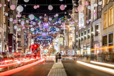 Londra 'nın kırmızı otobüsü Noel süslemeleri ve yoğun yaya trafiğiyle aydınlık bir caddeden geçiyor. Seyahat, tatil veya kentsel yaşam tarzı temaları için ideal