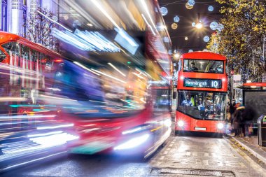 Londra 'nın kırmızı otobüsü Noel süslemeleri ve yoğun yaya trafiğiyle aydınlık bir caddeden geçiyor. Seyahat, tatil veya kentsel yaşam tarzı temaları için ideal