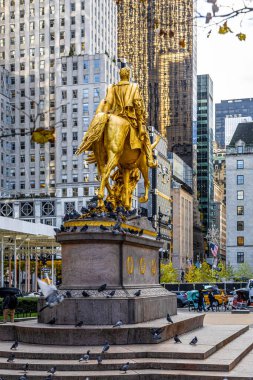 Central Park 'ın 5. caddesindeki altın binicilik anıtı Midtown Manhattan gökdelenlerinin arkasında, New York City, seyahat kampanyaları, kültür özellikleri ve editoryal kullanım için