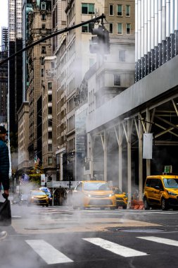 Trafik ve bayraklar hafifçe bulanık, kentsel altyapı, enerji ve kış hava durumu editörleri için ideal New York City Bulvarı 'ndaki rögar kapağından yoğun buhar dalgaları