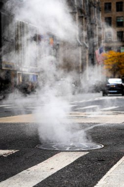 Trafik ve bayraklar hafifçe bulanık, kentsel altyapı, enerji ve kış hava durumu editörleri için ideal New York City Bulvarı 'ndaki rögar kapağından yoğun buhar dalgaları