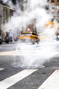 Trafik ve bayraklar hafifçe bulanık, kentsel altyapı, enerji ve kış hava durumu editörleri için ideal New York City Bulvarı 'ndaki rögar kapağından yoğun buhar dalgaları