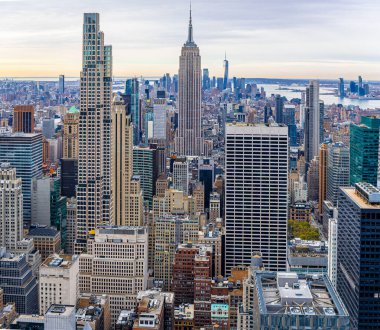 Panoramik Manhattan silueti Empire State binasının mavi gökyüzünün altında yer almaktadır; seyahat reklamları, emlak pazarlaması, kentsel iş temaları ve editoryal kullanım için idealdir.