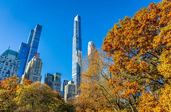 Central Park manzarası, New York 'ta açık mavi gökyüzü altında altın sonbahar ağaçları ve şehir kuleleri ile kaplıdır; seyahat, refah, emlak ve yaşam tarzı markalaşması için mükemmeldir.