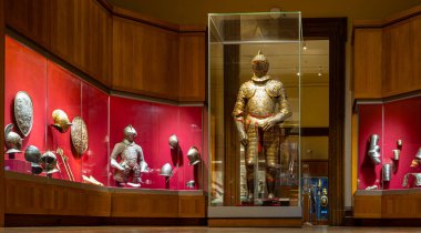 Müze galerisinde cam arkasında sergilenen ayrıntılı zırh ve antika silahlar; tarihi eğitim, kültür turizmi, yazı işleri ve sergiler için mükemmel