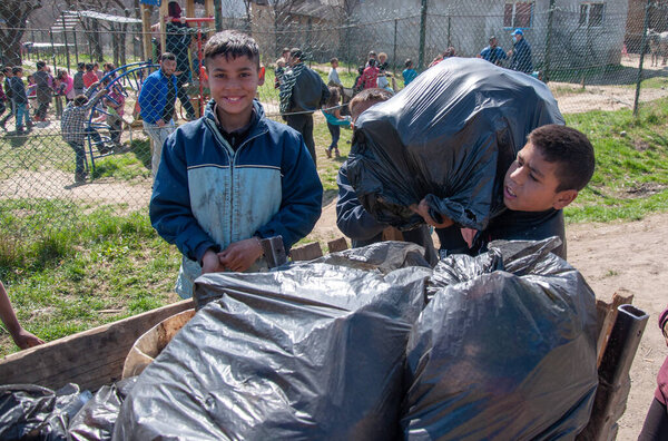 SEREDNIE, UKRAINE - APRIL 13, 2021: Romani childrens carry garbage during an environmental campaign in gypsy settlement