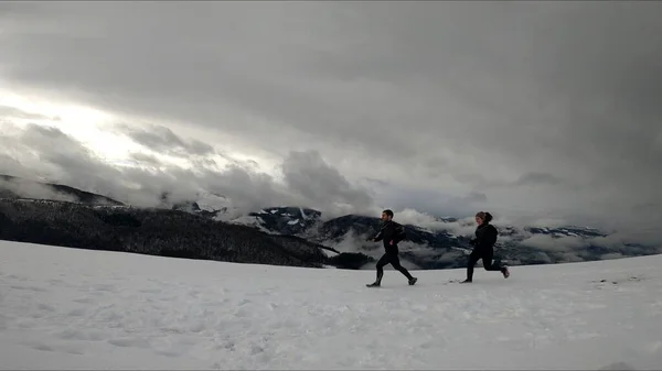 在雪山中奔跑的年轻夫妇 — 图库照片
