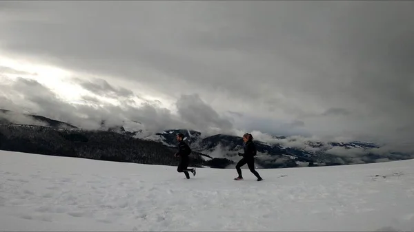 在雪山中奔跑的年轻夫妇 — 图库照片