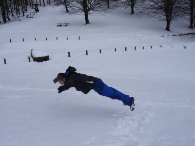 Genç adam karla oynuyor.