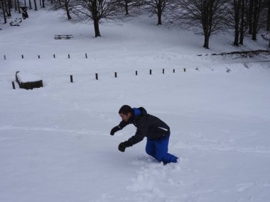 Genç adam karla oynuyor.