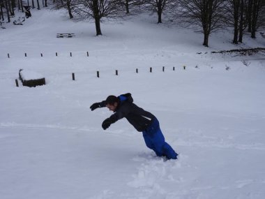 Genç adam karla oynuyor.