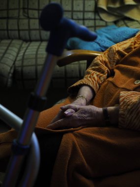 Yalnız ve yaşlı bir kadının elleri kanepeye oturur.