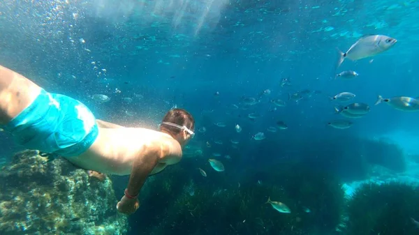 Menorca 'da şnorkelle yüzen genç adam 