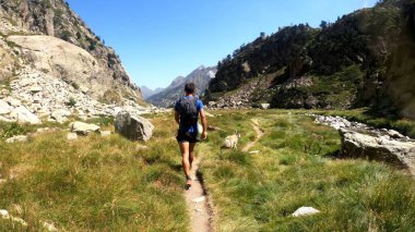 Genç adam dağlarda yürüyüş yapıyor.