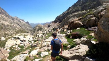 Genç adam dağlarda yürüyüş yapıyor.