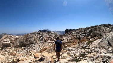 Genç adam dağlarda yürüyüş yapıyor.