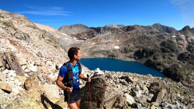 Genç adam dağlarda yürüyüş yapıyor.