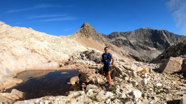 Genç adam dağlarda yürüyüş yapıyor.