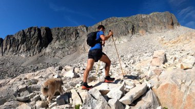 Genç adam dağlarda yürüyüş yapıyor.