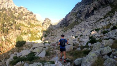 Genç adam dağlarda yürüyüş yapıyor.