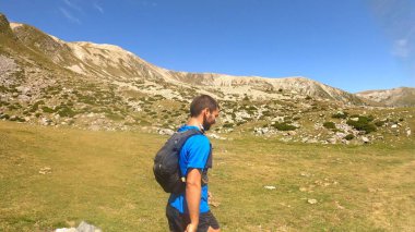 Genç adam dağlarda yürüyüş yapıyor.