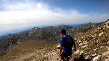 Genç adam dağlarda yürüyüş yapıyor.