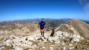 Genç adam dağlarda yürüyüş yapıyor.