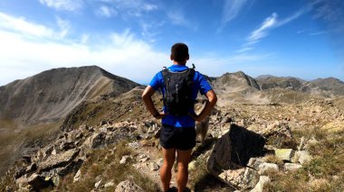 Genç adam dağlarda yürüyüş yapıyor.