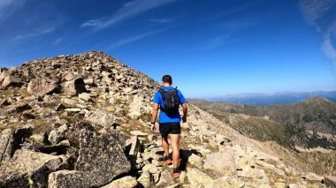 Genç adam dağlarda yürüyüş yapıyor.