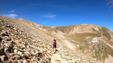 Dağlarda yürüyüş yapan genç bir kadın.