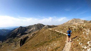 Genç adam dağlarda yürüyüş yapıyor.
