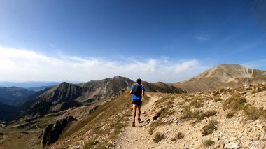 Genç adam dağlarda yürüyüş yapıyor.