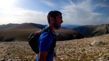 Genç adam dağlarda yürüyüş yapıyor.