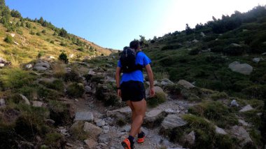 Genç adam dağlarda yürüyüş yapıyor.