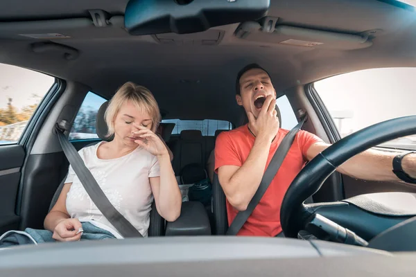 Hombre conductor cansado y somnoliento bosteza mientras está al lado de dormir esposa agotada. Conducción de coches a alta velocidad en carretera —  Fotos de Stock